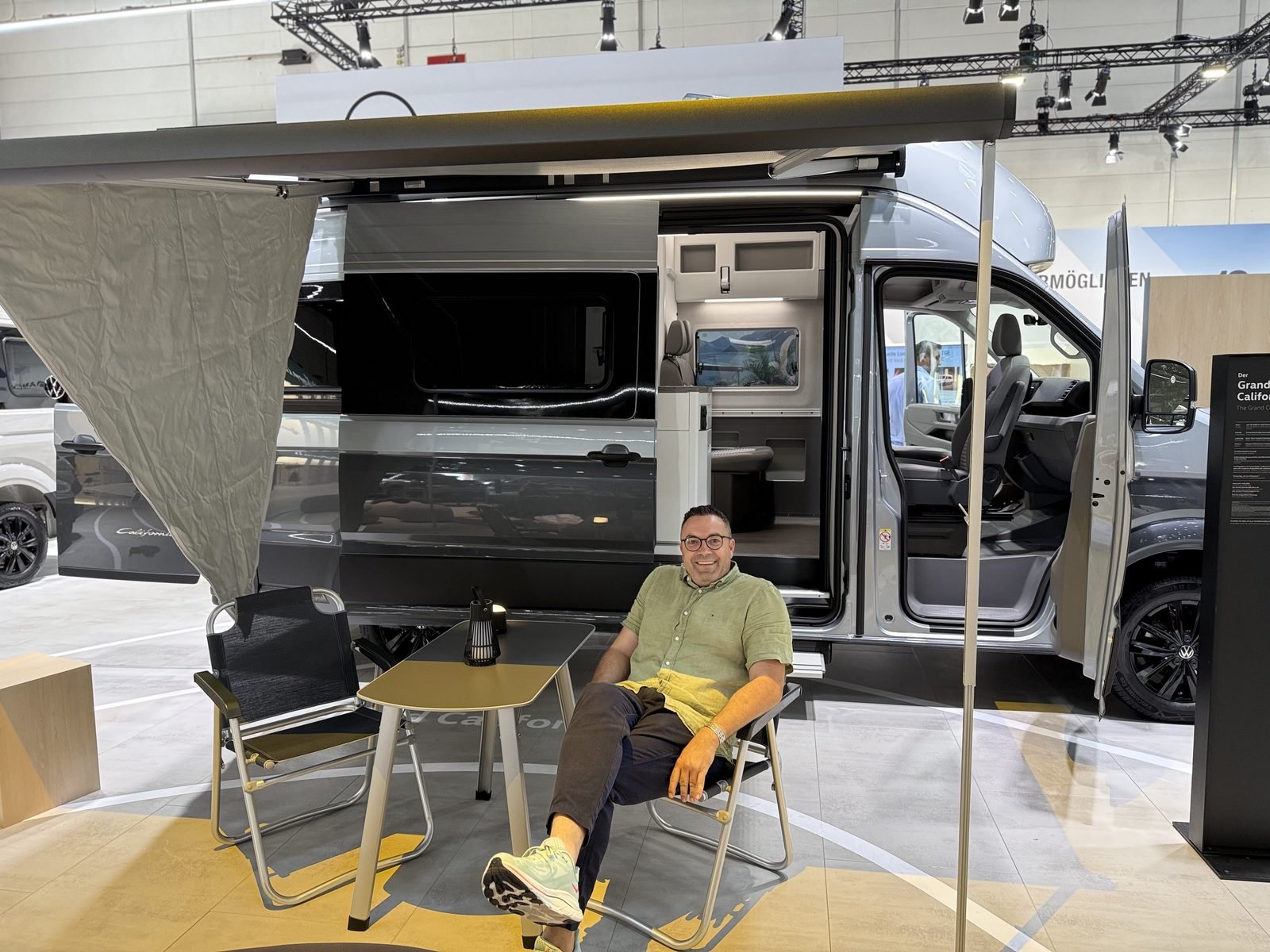 René Zacke von MARU sitzt vor dem VW Grand California 600 4MOTION Sondermodell DUNE – VAYARO Camping-Content für VW Nutzfahrzeughändler